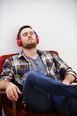 Man, headphones and nap in living room with music, song or podcast to relax on the weekend at home. Audio, streaming and internet radio with calm track in chair with digital and online listening