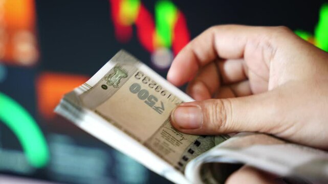 Counting Indian 500 rupee currency against stock market graph
