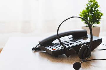 A black phone and headset sit on a table