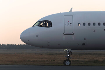 White passenger airplane on the runway at sunset