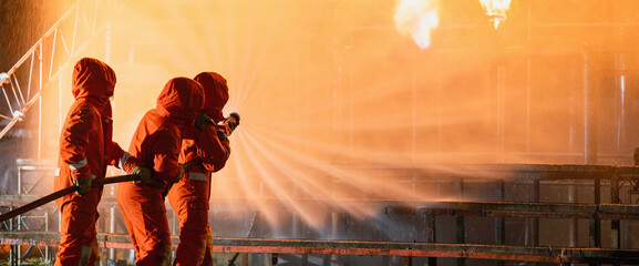 Three firefighters are spraying water on a fire
