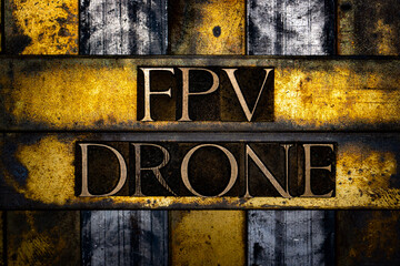 FPV Drone text in real authentic typeset letters on vintage textured silver grunge copper and gold background