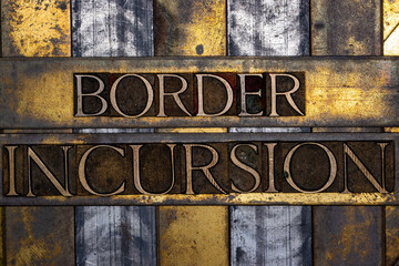 Border Incursion text in real authentic typeset letters on vintage textured silver grunge copper and gold background