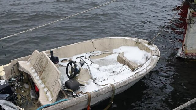 A snow-covered boat rocks on the waves