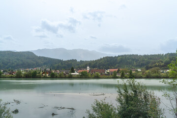 Fototapeta premium St. Niklas an der Drau Nebenfluss der Donau mit den Bergen im Hintergrund und dem Fluss im Vordergrund