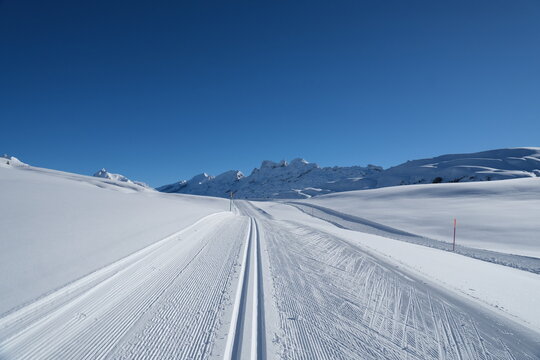 Prepared cross country skiing track or piste in Switzerland on a sunny blue sky winter day.