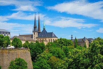 The image features Notre-Dame Cathedral and a section of the fortress wall in Luxembourg City. The Cathedral, completed in 1613, is the citys iconic landmark, offering stunning views and is a must