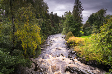 A dull, summer HDR image of the River Feshie and some autumnal colour taken from the bridge at Feshiebridge, Badenoch, Scotland