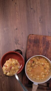 Persona versa la zuppa nelle ciotola con un mestolo, video verticale, zuppa di cicerchie e pasta