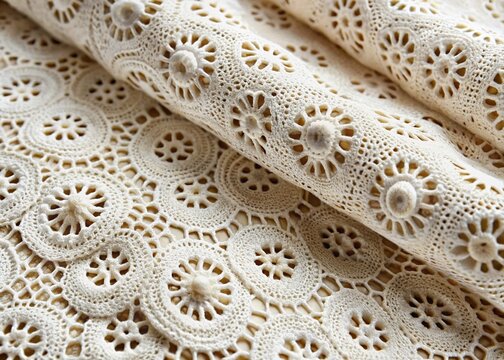 Delicate eyelet fabric with intricate lace-like patterns and small holes, showcasing subtle texture and woven threads,