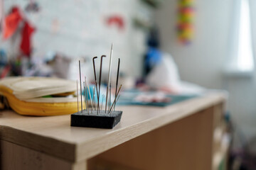 collection of diverse needles embedded in a foam block on a crafting table, symbolizing creativity...