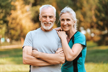 Smiling senior couple in love smiling while standing together in park, posing, looking at camera
