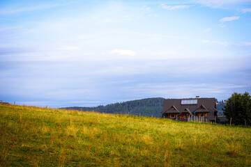 
natural landscape in the mountains with a sloping mountain meadow and a house on it