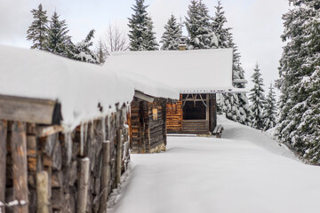 Wooden hut high in mountains covered in snow and surrounded with trees on a winter day