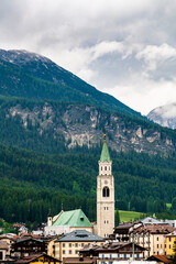 A panoramic view of the picturesque town of Cortina d'Ampezzo, nestled in the heart of the Dolomites. Majestic mountains rise in the background, offering a stunning natural backdrop.