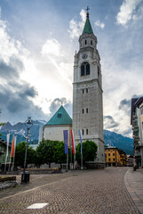 Obraz premium A view of the iconic church tower in the heart of Cortina d'Ampezzo. The architectural beauty of the tower stands tall against the backdrop of the surrounding Alpine scenery