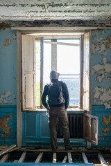 Person seen from the back standing by the window of abandoned mansion