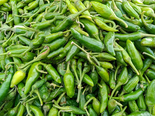 A Heap of raw Fresh Green Chillies is displayed on the stall in the market. Close Up Top view full frame background.