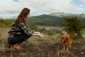 Serene moment Woman kneeling with dog on hill overlooking lake and mountains in peaceful travel scenery