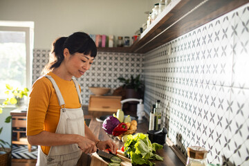 Asian woman chopping vegetables in kitchen for healthy meal prep