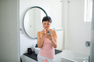 Asian woman brushing teeth in the bathroom