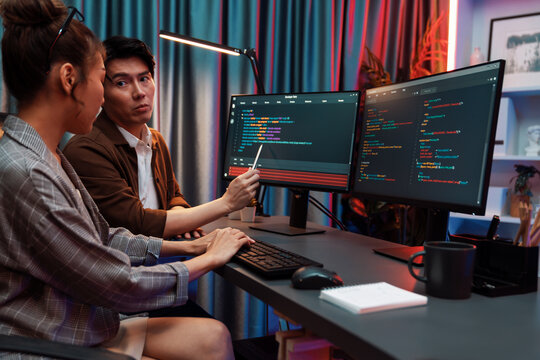 IT developers discussing with point to intelligent website development coder system running data online two screens information technology at neon light room at modern office. Infobahn.