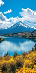 A mountain range with a lake in the foreground. The sky is blue and the clouds are white