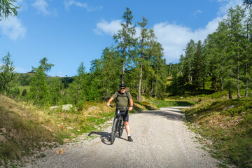 Naklejka premium Älterer Mann fährt mit seinem E Mountainbike durch die Bikewelt Karnische Alpen in Nassfeld in Kärnten Österreich