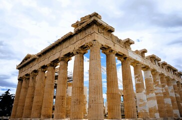Obraz premium Columns and marble remains of the mighty Parthenon on the hill of the Acropolis in Athens, sacred temples of the goddess Athena and tutelary goddess of the city - sightseeing and vacation in Greece
