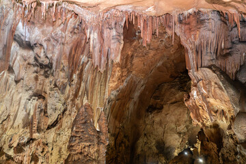A cave with brown walls and a ceiling covered in ice. The cave is dark and cold, with a sense of mystery and wonder.