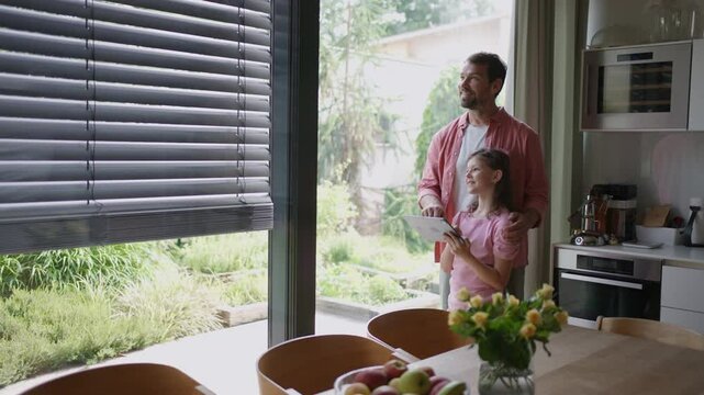 Father explaining daughter how to work with smart home automation system, adjusting metal blinders. Smart home technology for sustainable living.