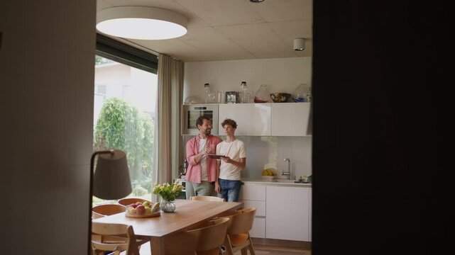 Father explaining son how to work with smart home automation system, adjusting lighting and air conditioning. Smart home technology for sustainable living.