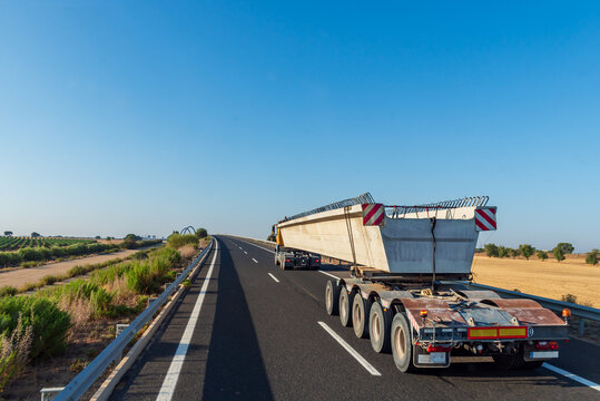 Truck with dolly transporting a large concrete beam along the highway, special transport.