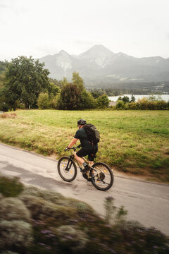 Mann f&auml;hrt mit Fahrrad am Egger Marterl mit Blick auf den Faaker See und die Berge dahinter in Villach in K&auml;rnten &Ouml;sterreich