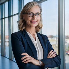 Head shot of confident blonde businesswoman in blue in front of glass wall.