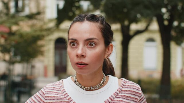 Oh my God, Wow. Young pretty amazed woman open mouth looking surprised through street with big open eyes, shocked by sudden situation, good shock news, something astonishing outdoors. Girl in city