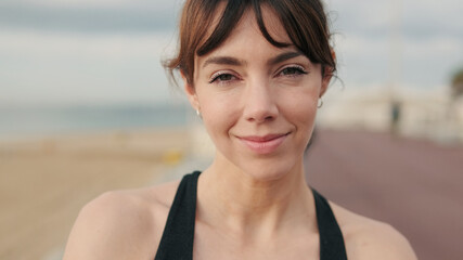 Portrait of calm european active and sporty girl looking at camera against the sea, fit woman