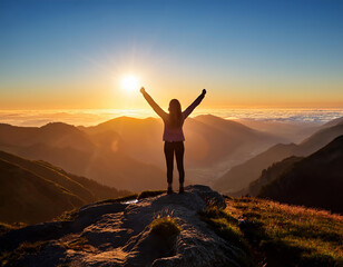 Fototapeta premium Hiker is celebrating reaching the summit by raising her arms in the air as the sun sets