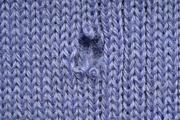 hole in a violet woollen jumper, hole in a purple woollen jumper, texture of a purple crocheted sweater as a background, a fragment of a purple crocheted front surface close up 
