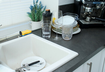 White ceramic kitchen sink and dirty unwashed dishes on kitchen table