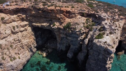 Aerial view of the sea caves of Cominotto uninhabited island near Comino, Maltese islands. Seagull flying in the frame. High quality photo