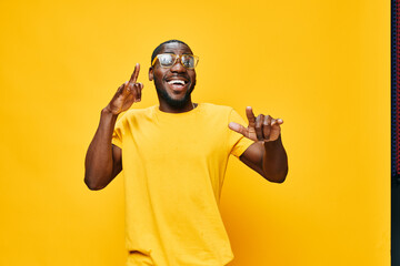 Smiling man with glasses celebrating against a bright yellow background, wearing a casual yellow t...