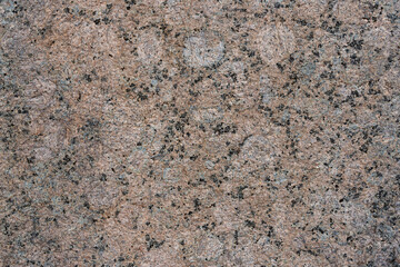 Granite texture. Natural pink granite with a grainy pattern. Stone background. Solid rough surface of rock. Durable construction and decoration material. Close-up.