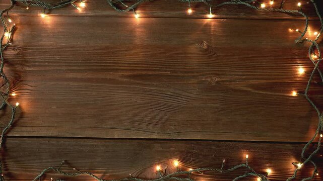 Christmas lights frame loop on rustic wooden background. Realistic garland on old wooden planks. 
