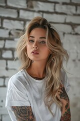 Naklejka premium A beautiful girl with tattoos stands in front of an oversize white t-shirt mockup with a light concrete backdrop