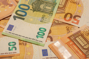 A stack of Euro banknotes with the numbers 100 and 50. The banknotes are mixed up.