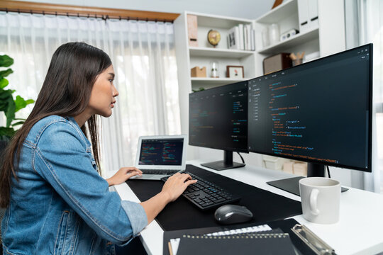 Young Asian in IT developer creating with typing online information on pc with coding program data of website application, wearing jeans shirt. surrounded by safety analysis two screens. Stratagem.