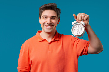 Happy man with alarm clock, blue background. Early morning, correct day routine