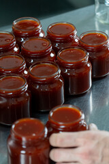 Jars of freshly made rosehip jam in an artisan factory. The jam, rich in color and texture, fills the glass jars to the brim, ready for sealing. Captured during production
