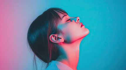 Naklejka premium A serene portrait of a young woman bathed in vibrant blue and pink lighting, conveying tranquility and introspection.